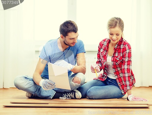 Image of smiling couple measuring wood flooring