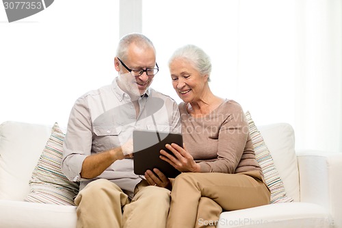 Image of happy senior couple with tablet pc at home