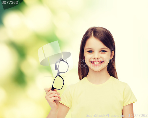 Image of smiling cute little girl holding black eyeglasses