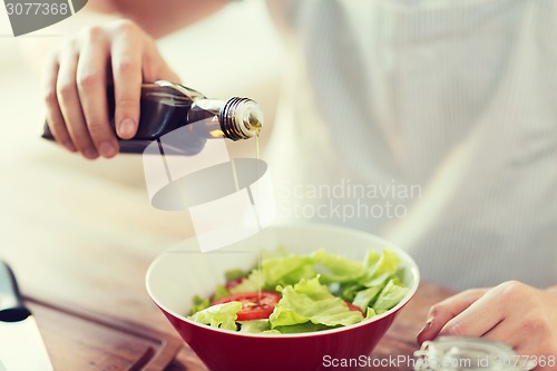 Image of close up of male hands flavouring salad in a bowl