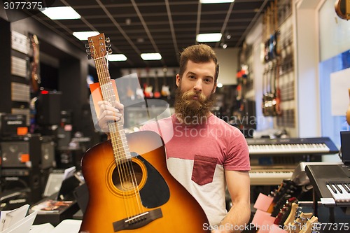Image of assistant or customer with guitar at music store