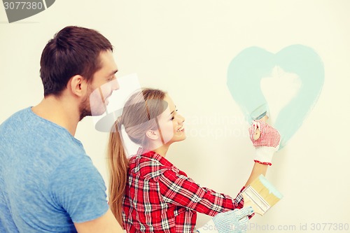 Image of smiling couple painting small heart on wall