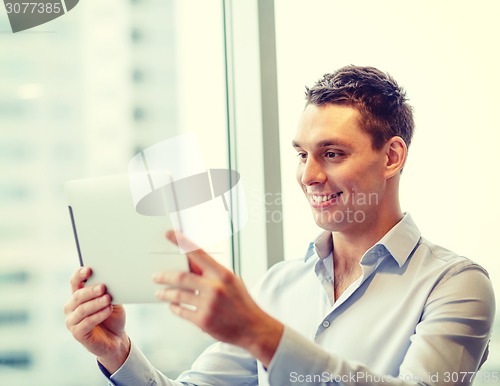 Image of smiling businessman with tablet pc in office