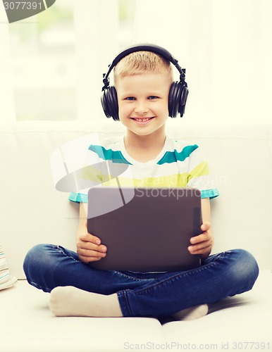 Image of little boy with tablet pc and headphones at home