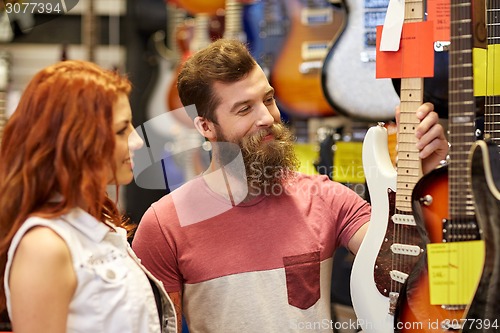 Image of couple of musicians with guitar at music store