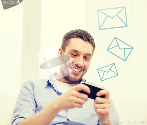 Image of smiling man with smartphone at home