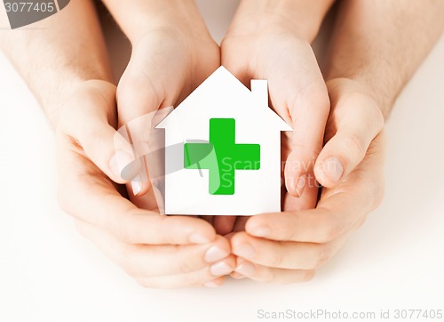 Image of hands holding paper house with green cross