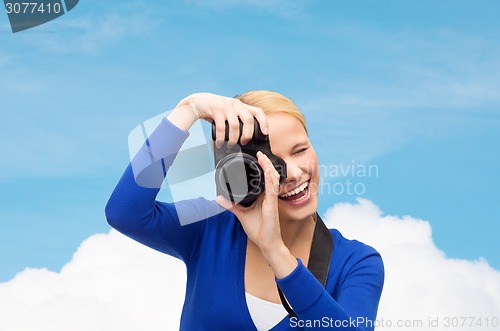 Image of smiling woman taking picture with digital camera