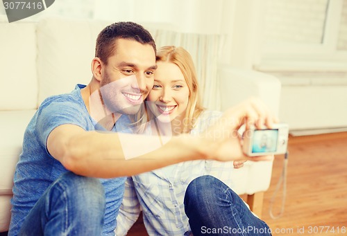 Image of smiling couple taking picture with digital camera