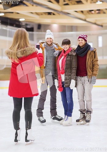 Image of happy friends taking photo on skating rink
