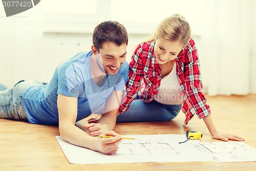 Image of smiling couple looking at blueprint at home