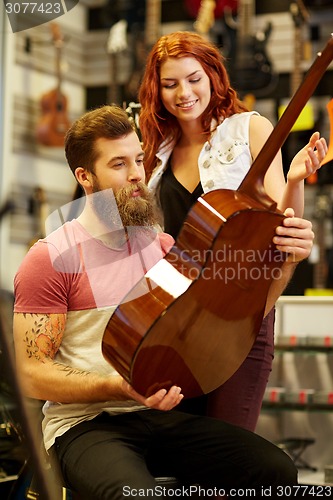 Image of couple of musicians with guitar at music store