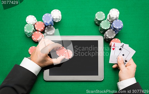 Image of casino poker player with cards, tablet and chips