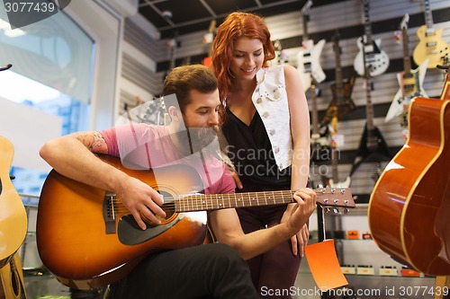 Image of couple of musicians with guitar at music store