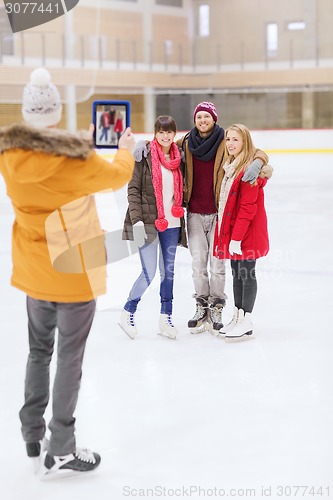 Image of happy friends taking photo on skating rink