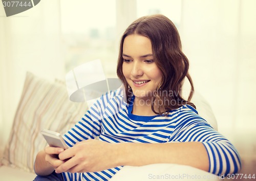 Image of smiling teenage girl with smartphone at home