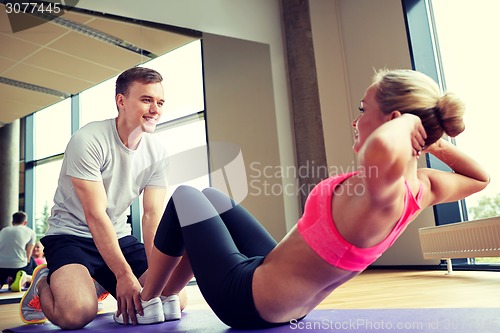 Image of woman with personal trainer doing sit ups in gym