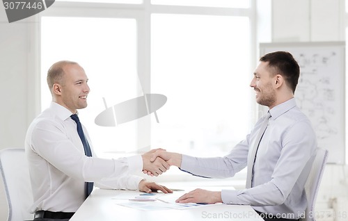 Image of two smiling businessmen shaking hands in office