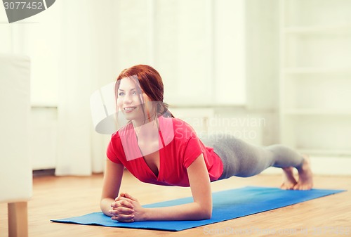 Image of smiling redhead teenage girl doing plank at home