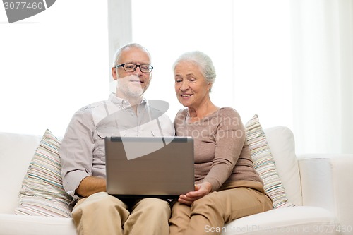 Image of happy senior couple with laptop at home