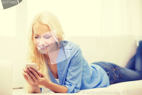 Image of smiling woman with smartphone at home