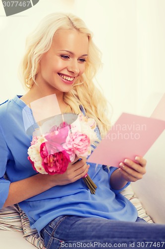 Image of smiling woman with card and bouquet of flowers