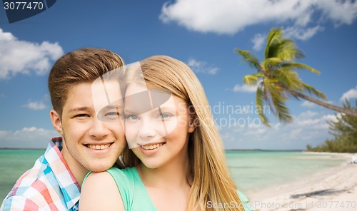 Image of smiling couple hugging over beach background