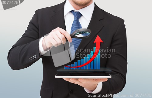 Image of businessman holding magnifier over tablet pc