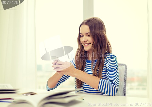 Image of smiling student girl with smartphone and books