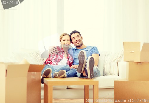 Image of smiling couple relaxing on sofa in new home