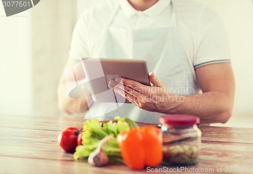 Image of closeup of man reading recipe from tablet pc