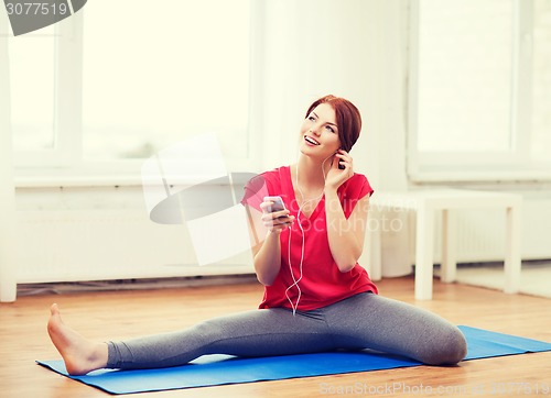 Image of smiling teenage girl streching on floor at home