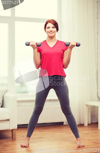 Image of smiling teenage girl exercising with dumbbells