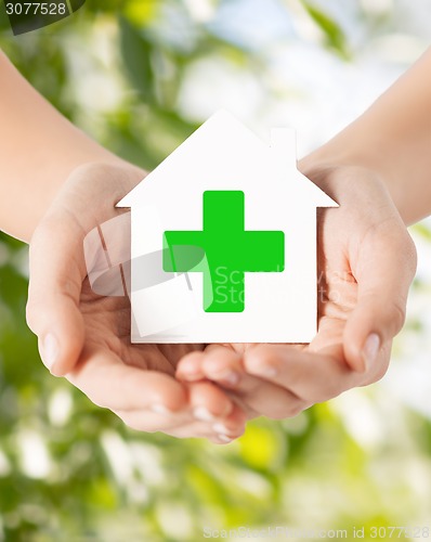 Image of hands holding paper house with green cross