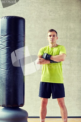 Image of man with boxing gloves and punching bag in gym