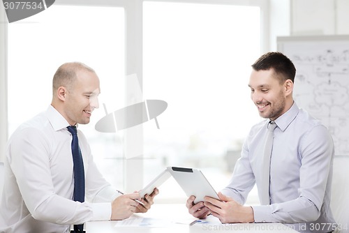 Image of two smiling businessmen with tablet pc in office