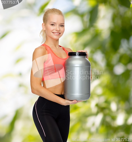 Image of smiling sporty woman with jar of protein