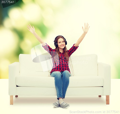 Image of teenage girl sitting on sofa with headphones