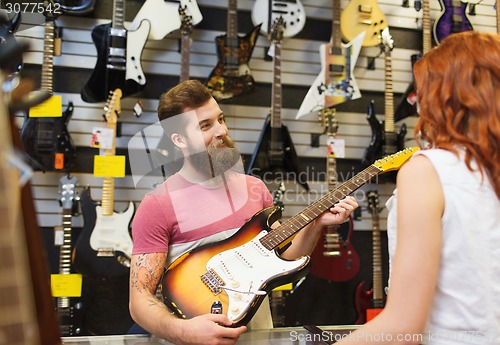 Image of assistant showing customer guitar at music store
