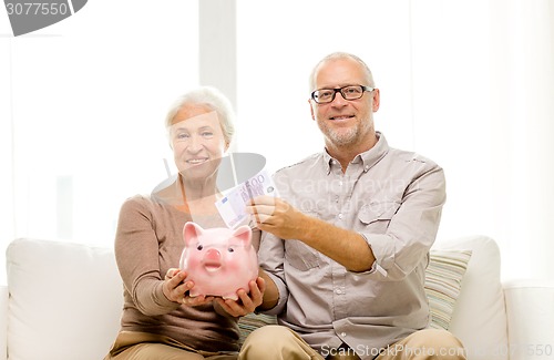 Image of senior couple with money and piggy bank at home