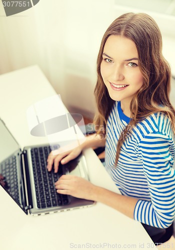 Image of smiling teenage gitl with laptop computer at home