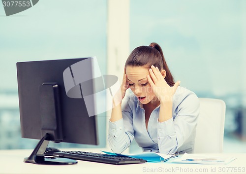 Image of stressed woman with computer and documents