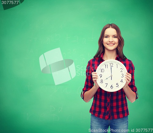 Image of young woman in casual clothes with wall clock