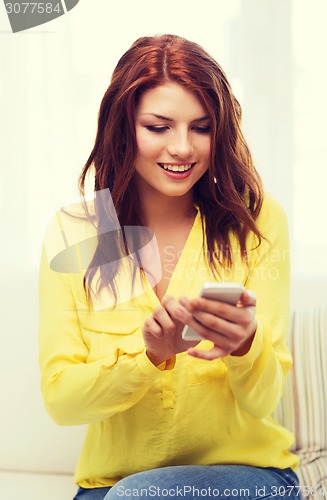 Image of smiling woman with smartphone at home