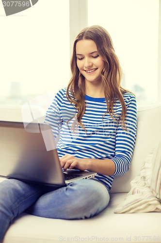 Image of smiling teenage girl with laptop computer at home