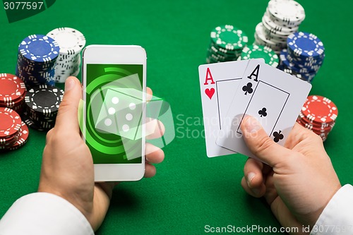 Image of casino player with cards, smartphone and chips