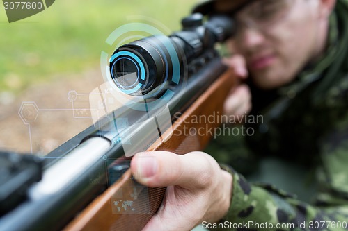 Image of close up of soldier or sniper with gun in forest