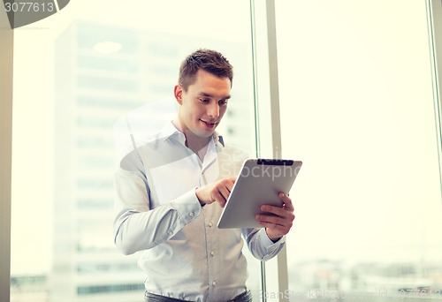 Image of smiling businessman with tablet pc in office