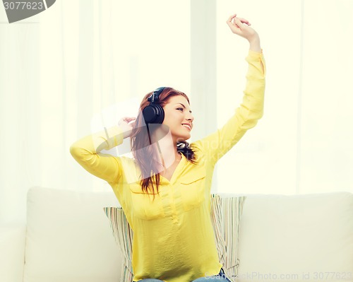 Image of teenage girl sitting on sofa with headphones