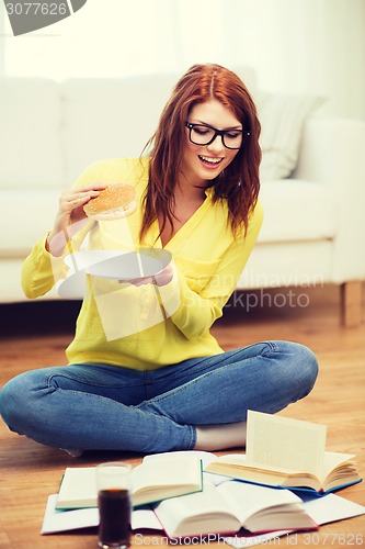 Image of student eating hamburger and doing homework